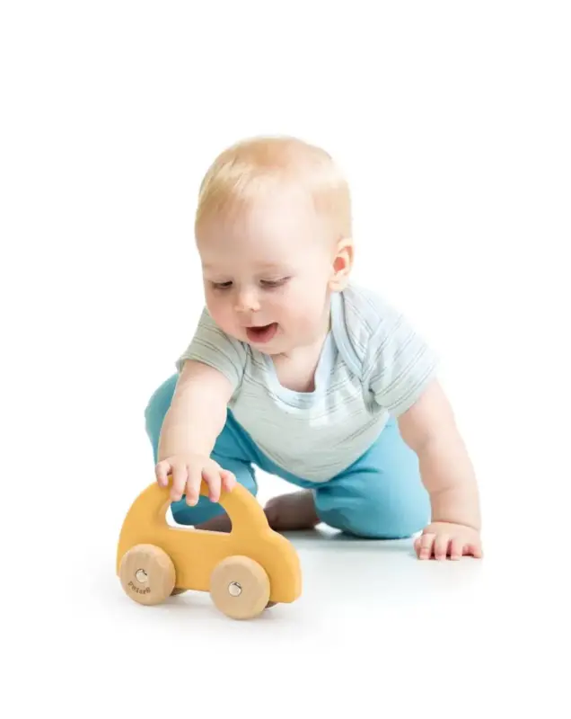 bērns rotaļājas ar koka automašīnu yellow